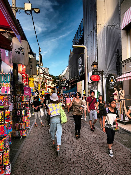Harajuku center Takeshite Street in HDR, Tokyo Tokyo, Japan - August 17, 2014: View of a people walking on Takeshite Street, which is a pedestrian-only street, during day time. On both sides are fashion boutiques while in background are cafes and restaurants too. Above the surrounding houses is dark blue sky coming from HDR filter. tokyo harajuku stock pictures, royalty-free photos & images