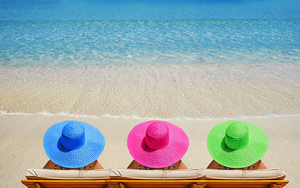 istock Three women on beach in bright hats traveling 529413670