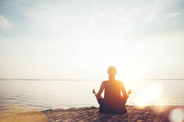 mujer haciendo prácticas de meditación en la playa - sunset sea tranquil scene sunrise fotografías e imágenes de stock