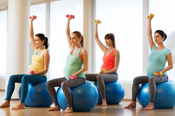 glückliche schwangere frau die ausübung auf fitball im fitnessraum - human pregnancy exercising relaxation exercise sport stock-fotos und bilder