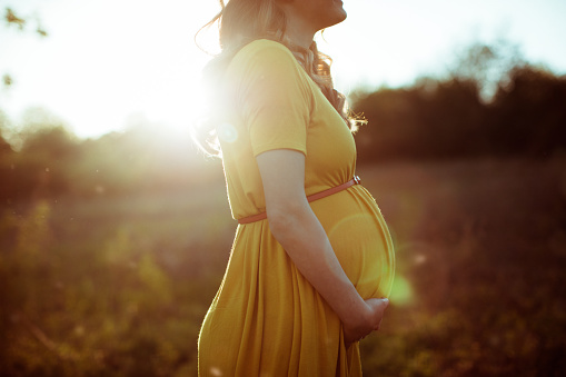 Photo of smiling pregnant woman relaxing in nature on a beautiful sunny day