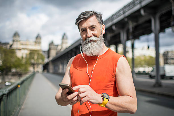 Setting up the app for the exercises Portrait of senior man runner setting up the app for the sport exercises. 60 69 years stock pictures, royalty-free photos & images