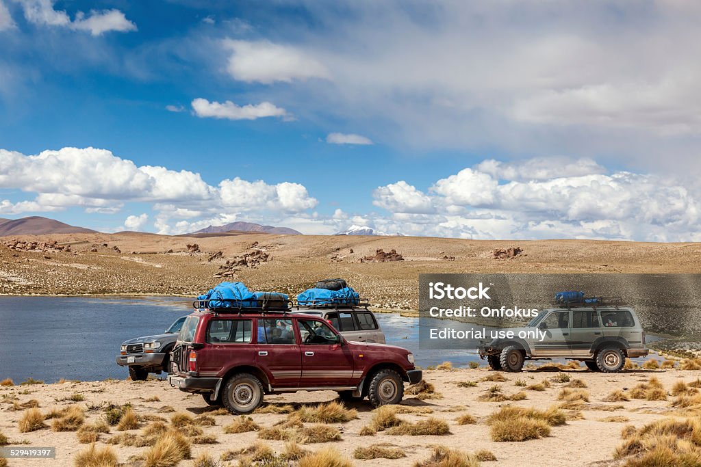 Group of Sports Utility Vehicles in the Bolivian Altiplano Bolivian Altiplano, Bolivia - March 01, 2011: 4x4 crossing a river in the Bolivian Altiplano, people doing a trek in high altitude in a Toyota Land Cruser 1999.  Toyota is a multinational automaker headquartered in Toyota, Aichi, Japan. 4x4 Stock Photo