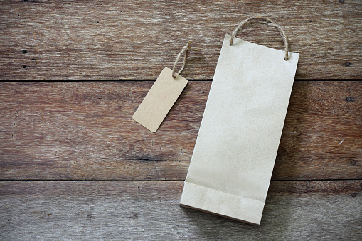 Price tag and paper shopping bag on wooden background