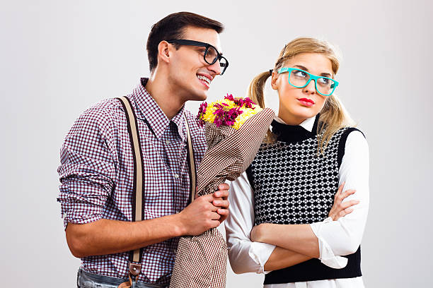 Please forgive me my dear! Nerdy man is giving  a bouquet of flowers to his girlfriend,he had made a mistake and he is hoping that she will forgive him. blind date stock pictures, royalty-free photos & images