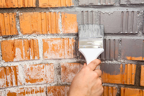 istock Human hand with grey colored brush painting brick wall 529421111