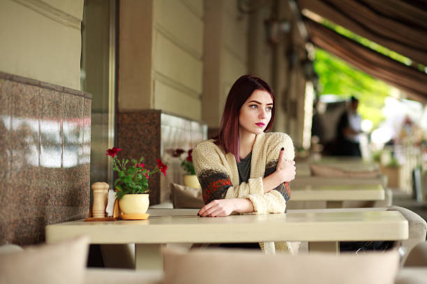 Thoughtful lonely woman in a cafe on a summer area