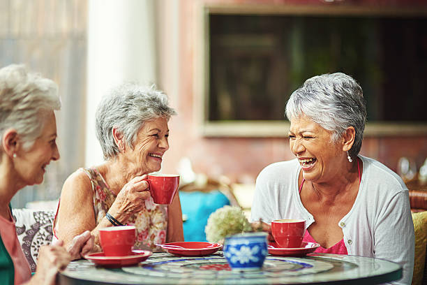Lifelong friends catching up over coffee Shot of a group of elderly friends having coffee together carefree senior stock pictures, royalty-free photos & images