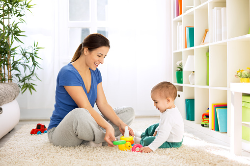 Happy smiling family playing with toys on floor