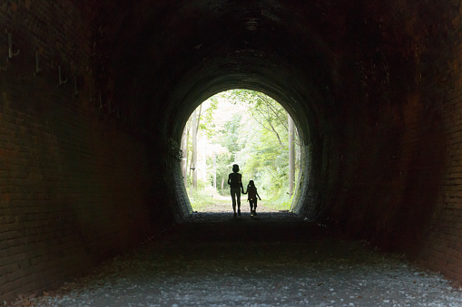 Parent and child who walk towards the exit of the tunnel