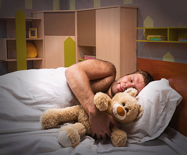 istock Sleeping man in bed with toy bear 529436271