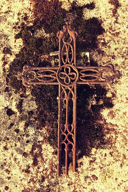 Broken iron rustic   crucifix on old mossy tombstone. Abandoned symbol of religion.