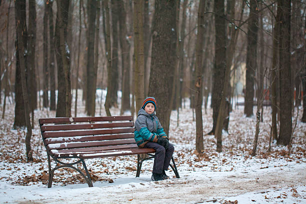 Lonely boy in snowy forest stock photo