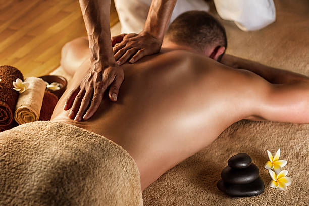 Deep tissue massage. Man has deep tissue massage on the back. Spa stones and frangipani flowers. man massage stock pictures, royalty-free photos & images