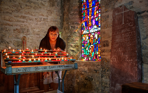 Mature hispanic woman praying at church candles