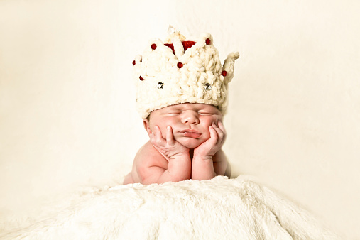 Newborn baby wearing a crown dormir en sus manos photo