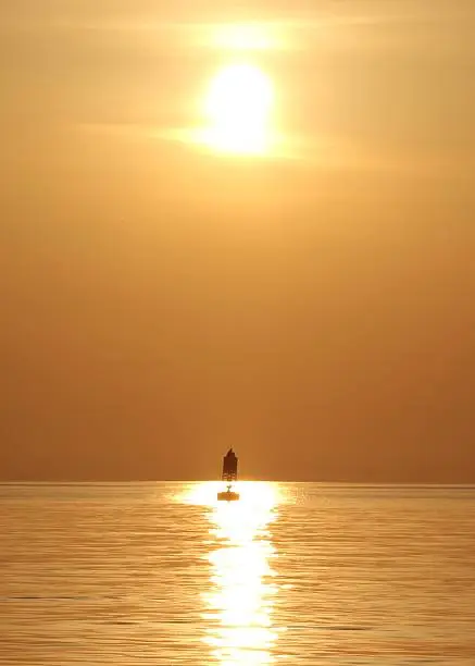 A navigational buoy is illuminated by the sun on a hazy day on the Chesapeake Bay.