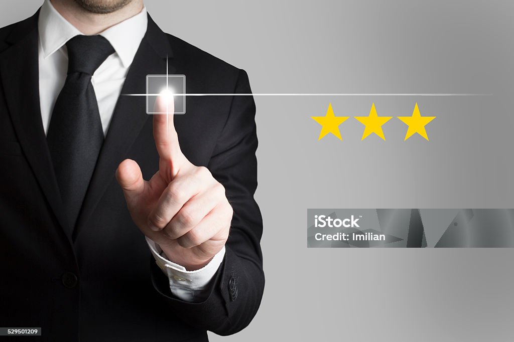 businessman pushing button three rating stars businessman in black suit pushing button three rating stars Adult Stock Photo