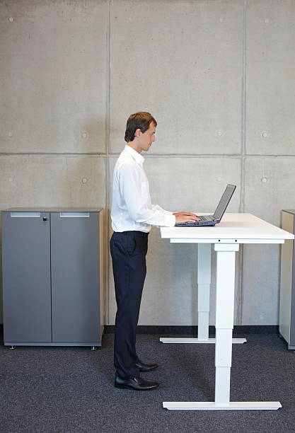 istock Businessman with eyeglasses standing at height adjustment table 529519171