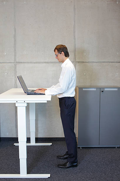 istock Businessman with eyeglasses standing at height adjustment table 529519189