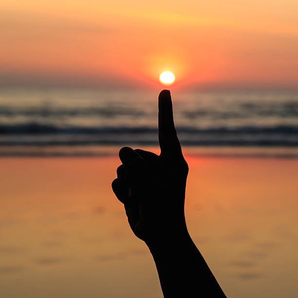 istock Silhouette of hands play with the sun at beach 529520437