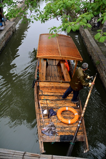 Zhujiajiao, China - May 17, 2014: canals of Zhujiajiao, an ancient town located in the Qingpu District of Shanghai. Boatmen sailing with a traditional wooden boat on a narrow waterway.
