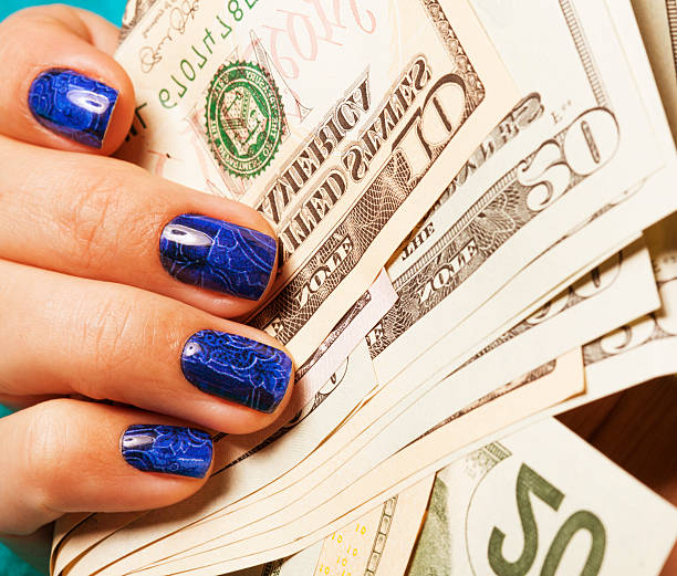 istock close up fingers with blue manicure holding dollars 529521417