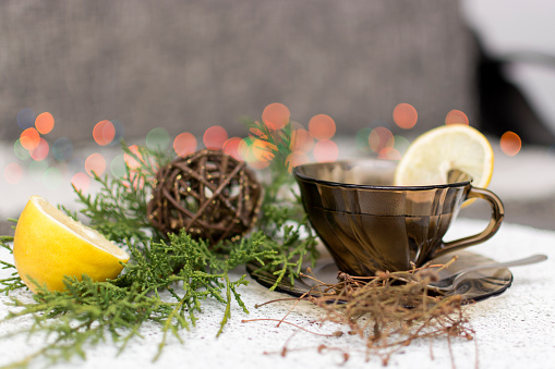 Cherry stems tea with lemon at the table with Christmas decoration and Christmas lights