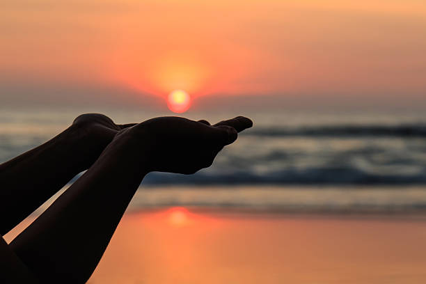 istock Silhouette of hands play with the sun at beach 529522963