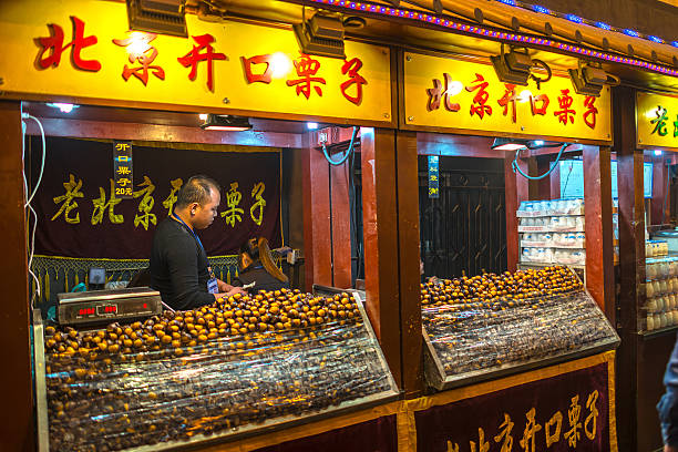 Wangfujing Snack Street Beijing, China - October 24, 2014: Wangfujing Snack Street at night. Chinese chef selling tradition Beijing Chestnut. Located in Beijing, China. wangfujing stock pictures, royalty-free photos & images
