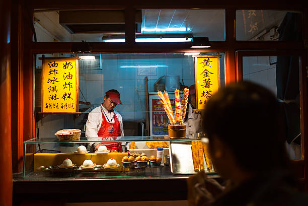 Wangfujing Snack Street Beijing, China - October 24, 2014: Wangfujing Snack Street at night. Chinese chef making tradition Chinese food. Located in Beijing, China. wangfujing stock pictures, royalty-free photos & images