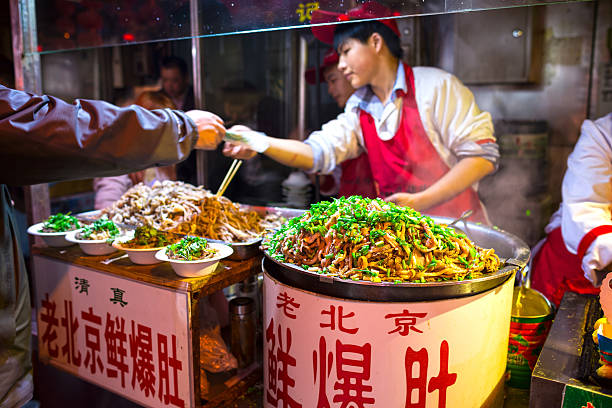 Wangfujing Snack Street Beijing, China - October 24, 2014: Wangfujing Snack Street at night. Chinese chef selling Ancient Beijing Soiled Pork Tripe. Located in Beijing, China. wangfujing stock pictures, royalty-free photos & images