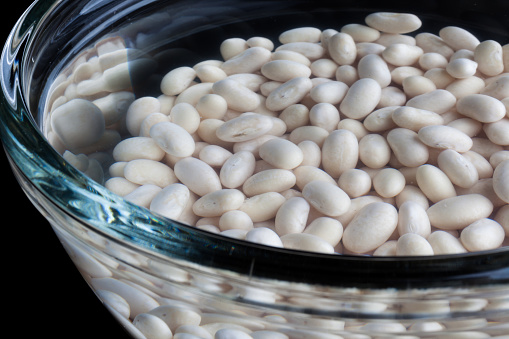 Closeup on white beans soaked in water in glass bowl