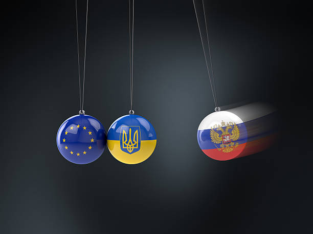 Conflict between Ukraine, Russia, and the EU - Newton's Cradle The conflict between Russia, the Ukraine, and the European Union (EU) illustrated with a Newton's Cradle. Russia hits Ukraine. desk toy stock pictures, royalty-free photos & images