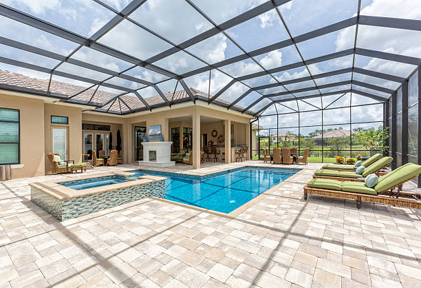 Outdoor dining room, bar and swimming pool all under a lanai screen.