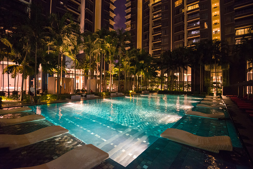 Nighttime swimming pool surrounded by palm trees. Kuala Lumpur, Malaysia.