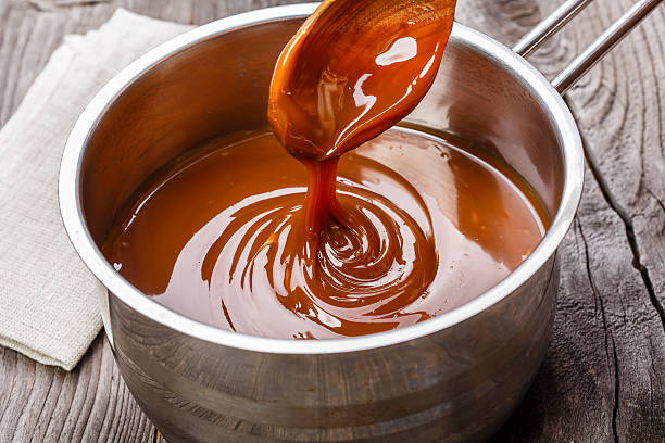caramello liquido viene versato in un salsiera - syrup foto e immagini stock