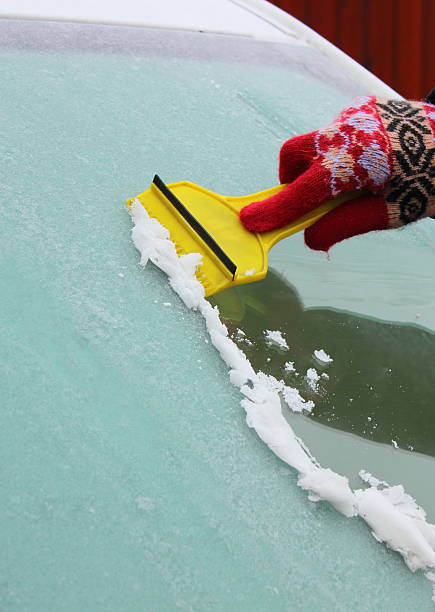 istock Hand of woman scraping ice from car windscreen 529597165