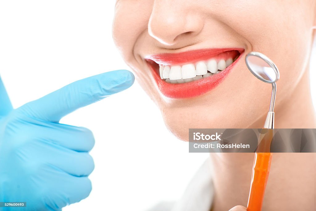 Woman with dental mirror on white background Young woman with dental mirror and wide healthy smile on white background Cut Out Stock Photo