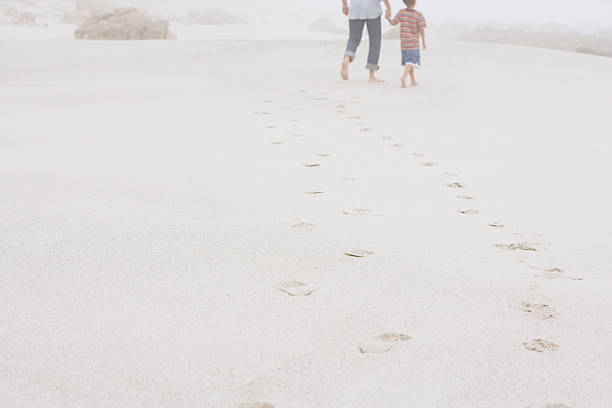 istock Father And Son Walking Leaving Behind Footprints On Sand 529651247