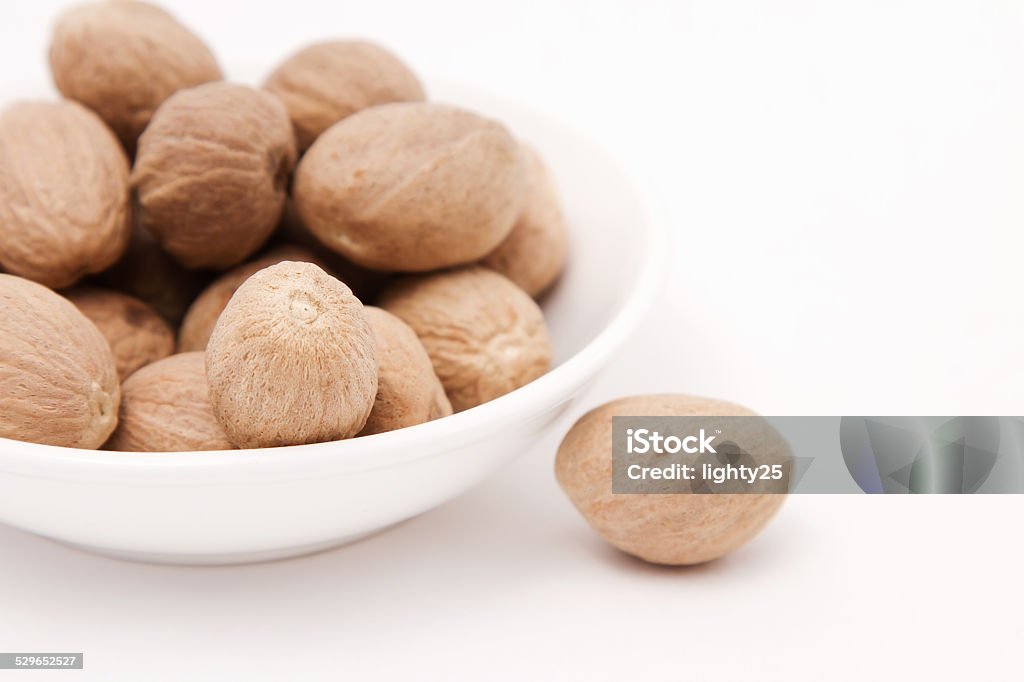 Whole nutmeg in white bowl Whole nutmeg in white bowl. Closeup view. Backgrounds Stock Photo