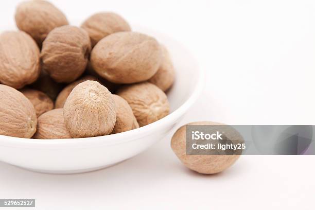 Whole Nutmeg In White Bowl Stock Photo - Download Image Now - Backgrounds, Bowl, Brown