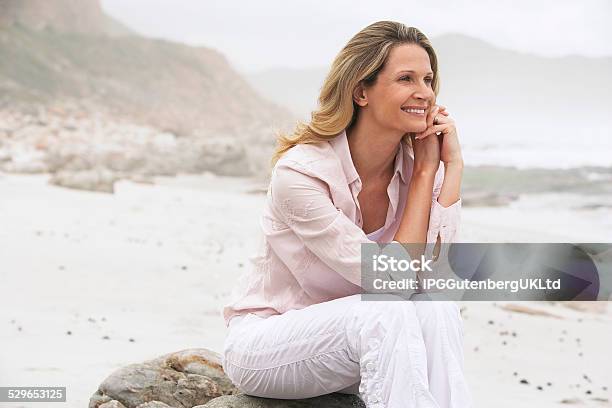 Happy Woman Relaxing On Rock At Beach Stock Photo - Download Image Now - Adult, Adults Only, Beach