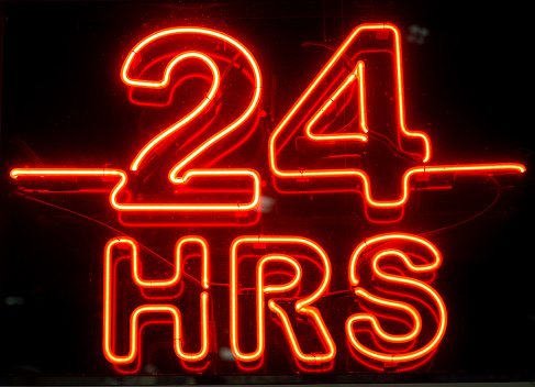 A closeup to a bright neon 24 hours sign at night