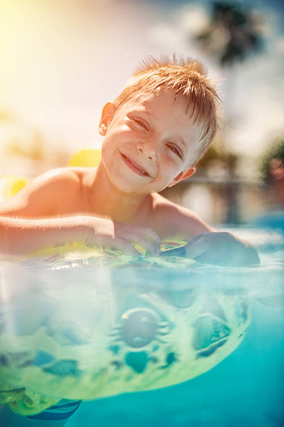 petit garçon s'amusant dans une piscine - floatation device flash photos et images de collection