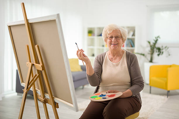 Elderly woman painting on a canvas