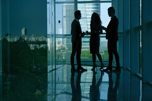 Silhouettes of business people chatting in dark office