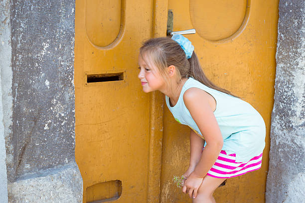 Listening through the orange door girl Listening through the orange door girl (open post well). Kutna Hora, Czech Republic eavesdropping stock pictures, royalty-free photos & images