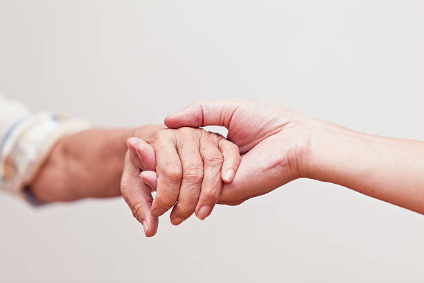 fornire supporto - holding hands human hand senior adult consoling foto e immagini stock