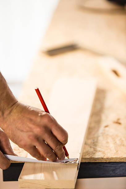 istock Carpenter measuring and marking wooden plank 529674890